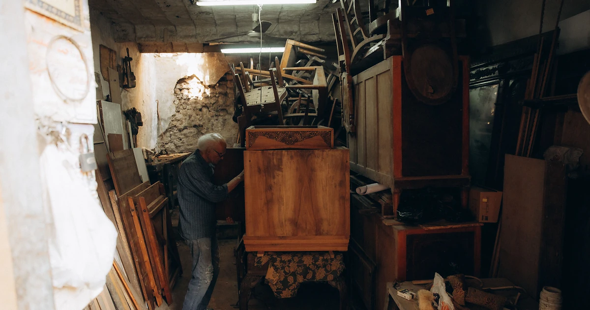 Artisan examinant un dossier de diagnostic énergétique sur un établi en bois, lumière naturelle de fenêtre d'atelier, illustrant la transition écologique des TPE et PME.