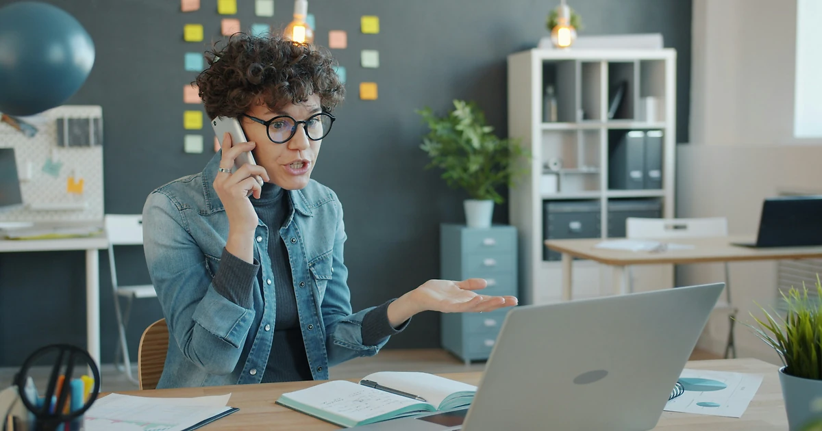 Expert sénior accompagnant un collaborateur à son bureau sur la gestion de la relation client