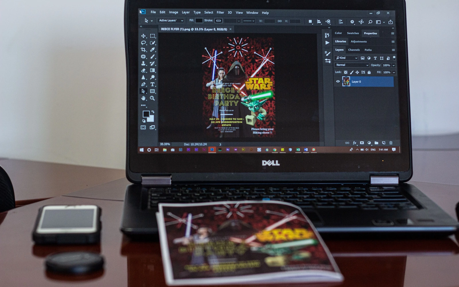 Un bureau avec un ordinateur allumer sur InDesign, avec un design créer et sur l'ordinateur un flyer du design imprimer.