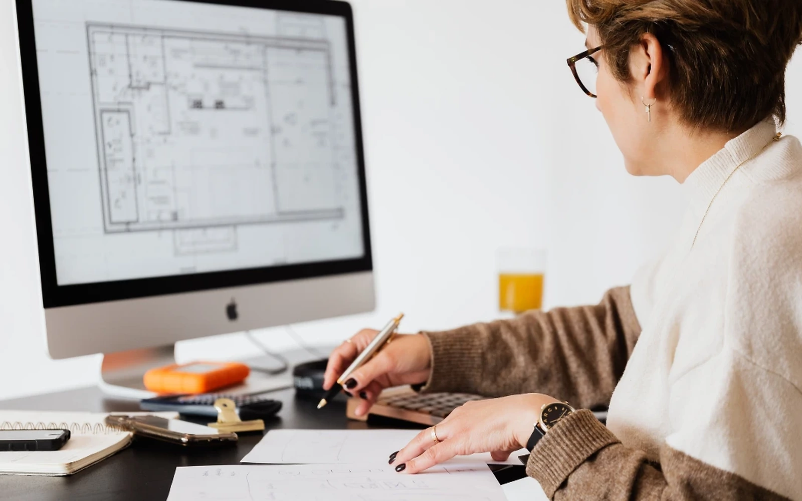 Expert en CAO accompagnant un ingénieur devant des plans techniques 3D, bureau d'ingénierie moderne